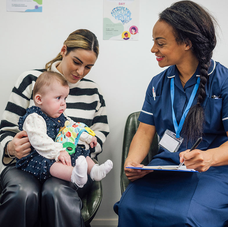Woman with baby sat next to nurse with a clipboard