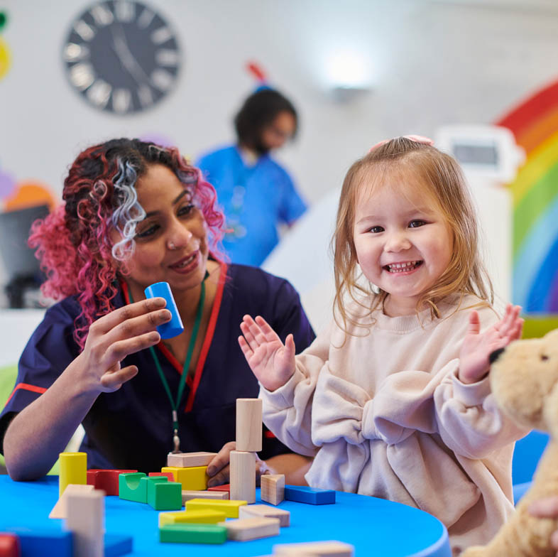 Adult with young child at a table with playing blocks